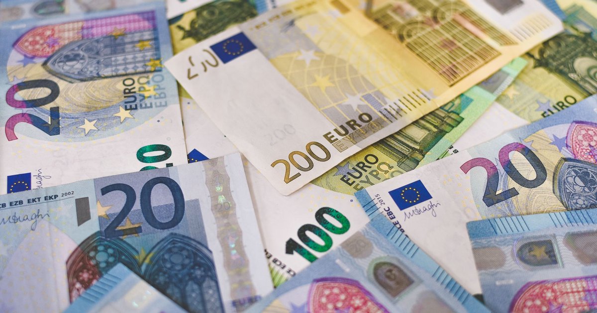 Factura de la luz en papel junto a monedas de euro sobre una mesa